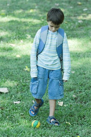 Boy wearing backpack, poised to kick ball Stock Photo - Premium Royalty-Free, Code: 633-01713965