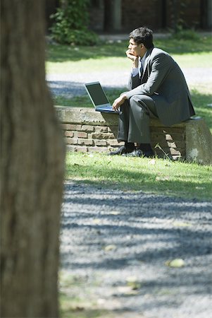 simsearch:633-01573622,k - Businessman sitting on low wall in park, using laZSop Foto de stock - Royalty Free Premium, Número: 633-01713981