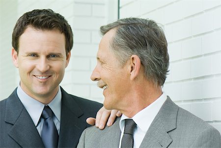 Two businessmen smiling together, one looking at camera Stock Photo - Premium Royalty-Free, Code: 633-01837067