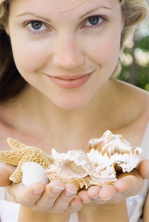 simsearch:695-03378760,k - Woman holding up handfuls of seashells, smiling at camera Foto de stock - Sin royalties Premium, Código: 633-01837226