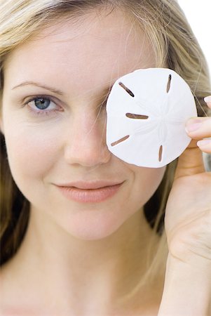 Woman covering one eye with sand dollar, smiling at camera, portrait Foto de stock - Royalty Free Premium, Número: 633-01837228