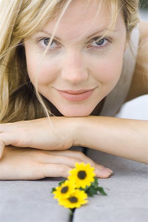 simsearch:633-02231795,k - Young woman lying on stomach next to flowers, head resting on arms, smiling at camera Foto de stock - Sin royalties Premium, Código: 633-01837223