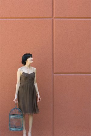 Woman standing, holding emZSy bird cage, looking up Fotografie stock - Premium Royalty-Free, Codice: 633-01837255