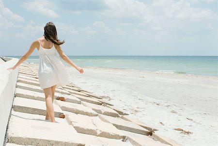 simsearch:633-01837235,k - Young woman walking along low wall at the beach, rear view Stock Photo - Premium Royalty-Free, Code: 633-01992443