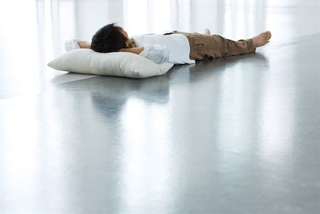 Man lying on floor with head on pillow, full length Stock Photo - Premium Royalty-Free, Code: 633-01992537