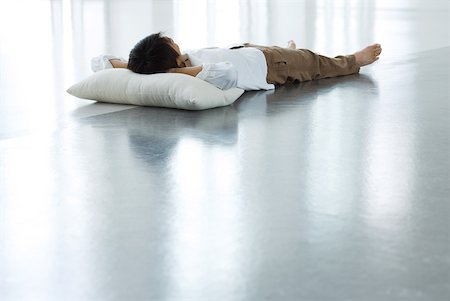 floor cushion - Man lying on floor with head on pillow, full length Stock Photo - Premium Royalty-Free, Code: 633-01992537