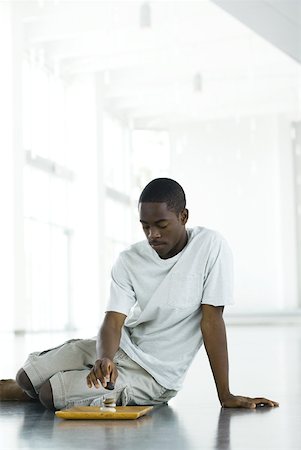 simsearch:695-05767562,k - Teen boy sitting on floor, stacking rocks on tray Stock Photo - Premium Royalty-Free, Code: 633-01992542