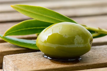 Olive and sprig of leaves on wood table, close-up Foto de stock - Sin royalties Premium, Código: 633-01992703