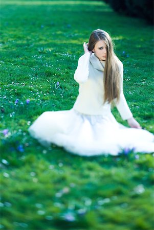 Teenage girl sitting in grass, hair partially covering face, looking away Stock Photo - Premium Royalty-Free, Code: 633-01992725