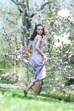 simsearch:633-01992711,k - Young woman in dress walking in meadow, looking over shoulder, low angle view Stock Photo - Premium Royalty-Free, Code: 633-01992721