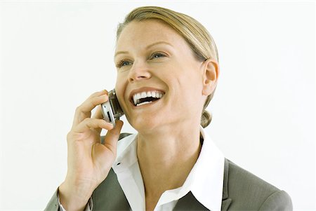 simsearch:695-03380514,k - Businesswoman using cell phone, smiling, looking away Fotografie stock - Premium Royalty-Free, Codice: 633-01992770