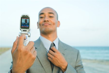 simsearch:633-01574593,k - Businessman photographing self with cell phone at the beach, smiling, adjusting tie Stock Photo - Premium Royalty-Free, Code: 633-01992799