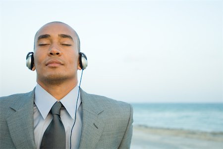 simsearch:632-01828543,k - Businessman listening to headphones at the beach, eyes closed, close-up Foto de stock - Royalty Free Premium, Número: 633-01992806