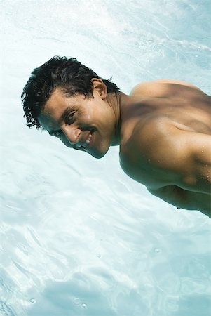 simsearch:633-03444513,k - Homme penché sur piscine, souriant par-dessus l'épaule à la caméra Photographie de stock - Premium Libres de Droits, Code: 633-01992933