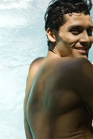 simsearch:633-03444513,k - Homme en piscine, souriant par-dessus l'épaule à la caméra Photographie de stock - Premium Libres de Droits, Code: 633-01992946