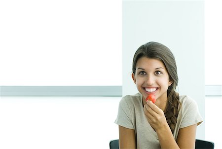 simsearch:693-06021794,k - Teen girl holding up strawberry to mouth, smiling Stock Photo - Premium Royalty-Free, Code: 633-02044200