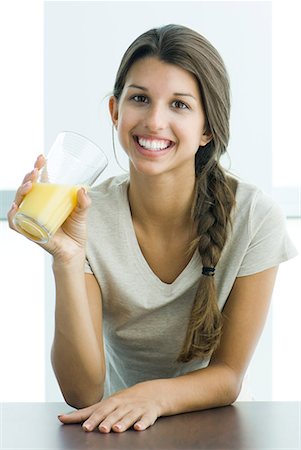 Teen girl drinking glass of orange juice, smiling at camera Stock Photo - Premium Royalty-Free, Code: 633-02044203