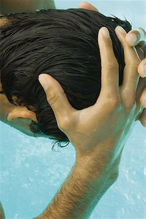 simsearch:632-05604352,k - Man bending over swimming pool, wetting head with water, cropped rear view Stock Photo - Premium Royalty-Free, Code: 633-02044321