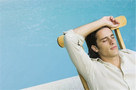 simsearch:695-03377120,k - Man sitting in lounge chair beside swimming pool, eyes closed, high angle view Foto de stock - Royalty Free Premium, Número: 633-02044334