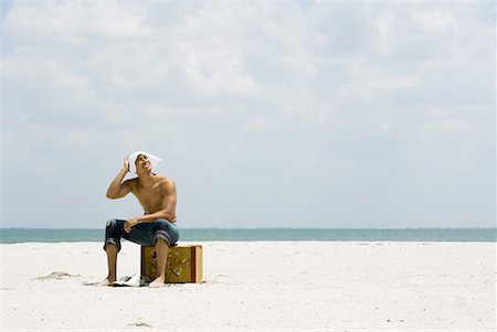 en détresse - Homme assis sur la valise à la plage, couvrant la tête avec le mouchoir, en levant vers le soleil Photographie de stock - Premium Libres de Droits, Code: 633-02044613