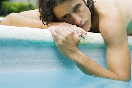 simsearch:632-01146602,k - Man lying on edge of pool with elbow dangling in water, looking at camera Stock Photo - Premium Royalty-Free, Code: 633-02066003