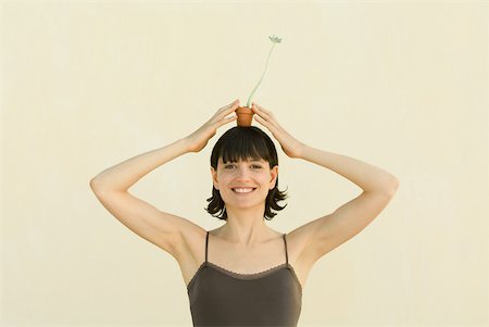 simsearch:696-03402861,k - Woman holding small potted plant on head, smiling at camera, portrait Foto de stock - Royalty Free Premium, Número: 633-02066083