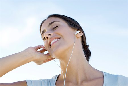 Female listening to earphones, smiling, eyes closed, low angle view Stock Photo - Premium Royalty-Free, Code: 633-02066108