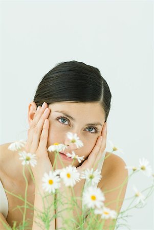Woman behind chamomile plant, holding head, looking up Stock Photo - Premium Royalty-Free, Code: 633-02128596