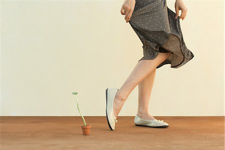 feet low angle view - Woman walking beside potted plant, holding skirt, cropped view Stock Photo - Premium Royalty-Free, Code: 633-02128614