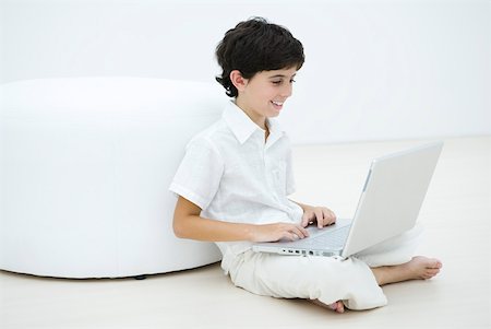 Boy sitting cross-legged on the floor using laZSop Foto de stock - Sin royalties Premium, Código: 633-02128638
