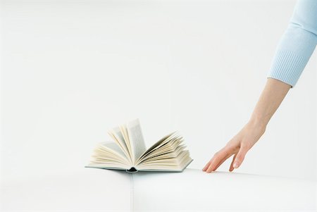 simsearch:633-02231822,k - Arm reaching for book, flipped open Stock Photo - Premium Royalty-Free, Code: 633-02128777