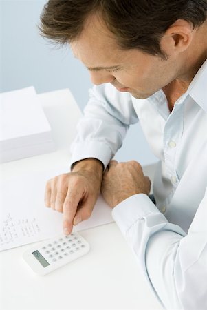Man using calculator, sitting at table, high angle view Foto de stock - Sin royalties Premium, Código: 633-02128781