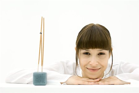 simsearch:633-01275048,k - Woman resting head on arms beside incense, smiling at camera Stock Photo - Premium Royalty-Free, Code: 633-02231772