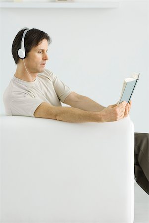 simsearch:632-02745314,k - Mature man sitting in armchair, reading book and listening to headphones Foto de stock - Sin royalties Premium, Código: 633-02231783