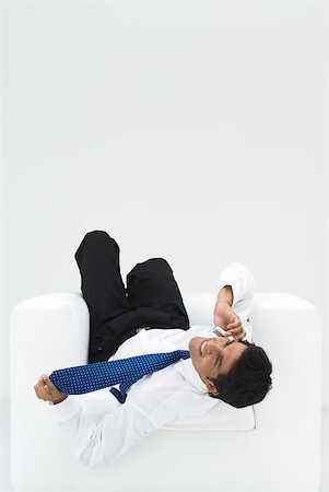 simsearch:695-03380514,k - Businessman lying upside down in armchair, talking on the phone Stock Photo - Premium Royalty-Free, Code: 633-02231843