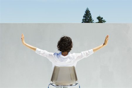 Woman seated facing wall, arms outstretched, rear view Stock Photo - Premium Royalty-Free, Code: 633-02345907