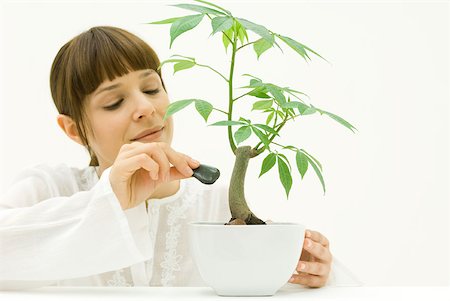 Woman carefully placing stone at base of potted plant Stock Photo - Premium Royalty-Free, Code: 633-02345901