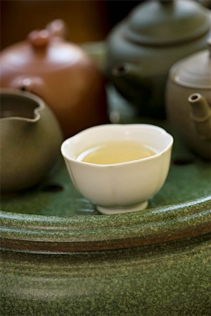 Tea cup full of tea placed before several teapots on tea tray Stock Photo - Premium Royalty-Free, Code: 633-02417816