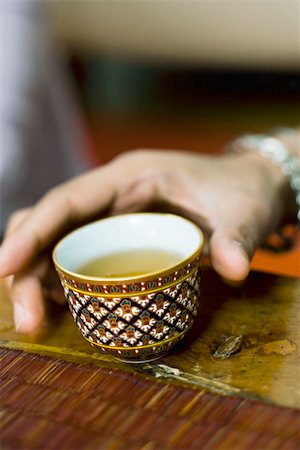 Hand reaching for colorful tea cup full of tea Stock Photo - Premium Royalty-Free, Code: 633-02417817