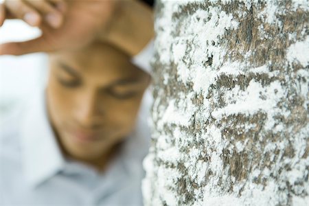 simsearch:696-03402108,k - Man leaning against tree trunk, focus on foreground Stock Photo - Premium Royalty-Free, Code: 633-02417953