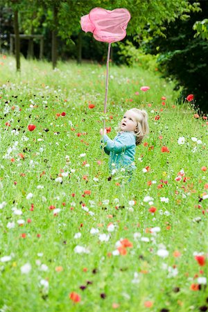 Little girl holding up butterfly net, standing in field of flowers Stock Photo - Premium Royalty-Free, Code: 633-02417965