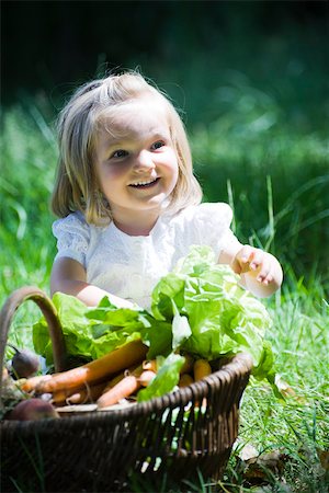 Little girl behind basket of vegetables, smiling and looking away Stock Photo - Premium Royalty-Free, Code: 633-02417985
