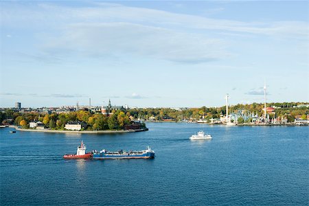 Sweden, Stockholm, Lake Malaren, tugboat pushing barge, city in background Foto de stock - Sin royalties Premium, Código: 633-02691298