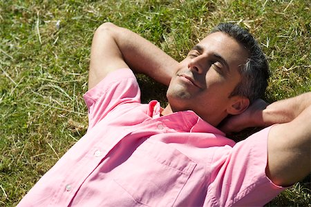 person lying on back hands behind head - Homme couché sur l'herbe avec les mains derrière la tête et les yeux fermés Photographie de stock - Premium Libres de Droits, Code: 633-03194685