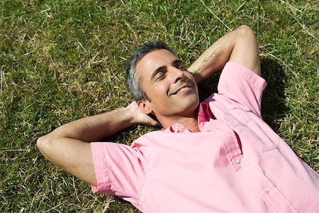 Man lying on grass with hands behind head and eyes closed, sprig of grass in mouth Foto de stock - Sin royalties Premium, Código: 633-03194687