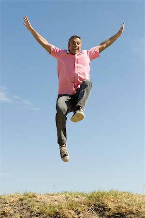 dynamic - Excited man jumping into the air with arms raised Stock Photo - Premium Royalty-Free, Code: 633-03194699