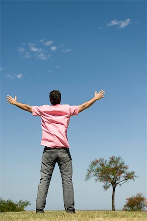 Man standing outdoors with arms raised, full length, rear view Stock Photo - Premium Royalty-Free, Code: 633-03194693