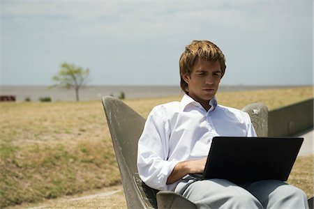 simsearch:633-03194783,k - Man using laZSop computer outdoors, open field in background Stock Photo - Premium Royalty-Free, Code: 633-03194778