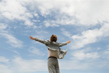 Businessman with arms outstretched against cloudy sky, rear view Stock Photo - Premium Royalty-Free, Code: 633-03194771