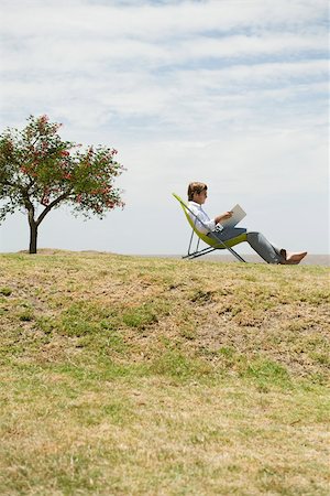 simsearch:633-03194783,k - Man relaxing outdoors reading through binder Stock Photo - Premium Royalty-Free, Code: 633-03194783